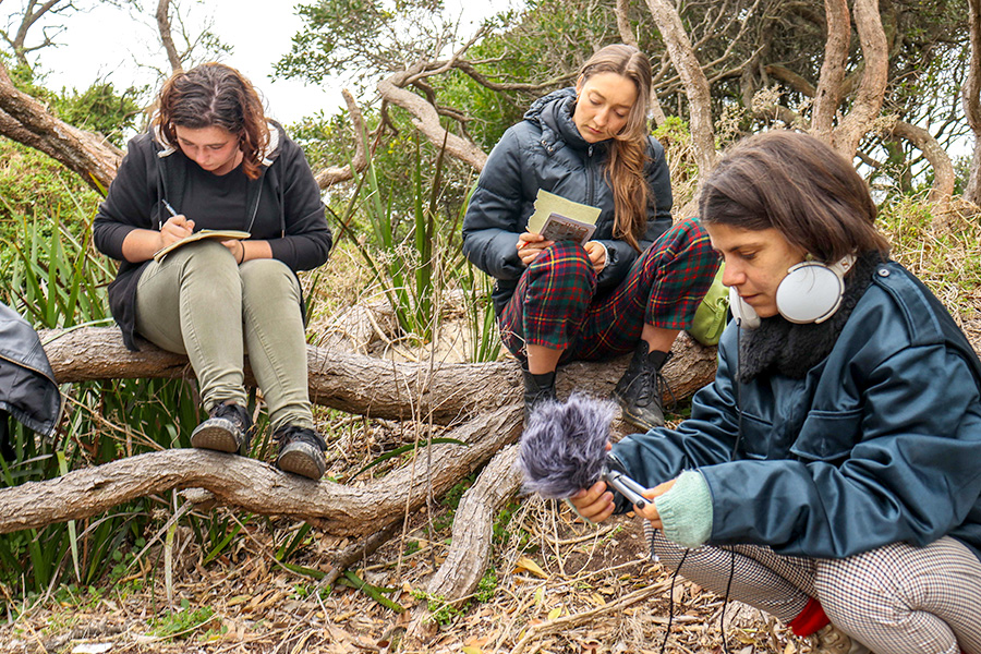 students sitting in a forest recording audio