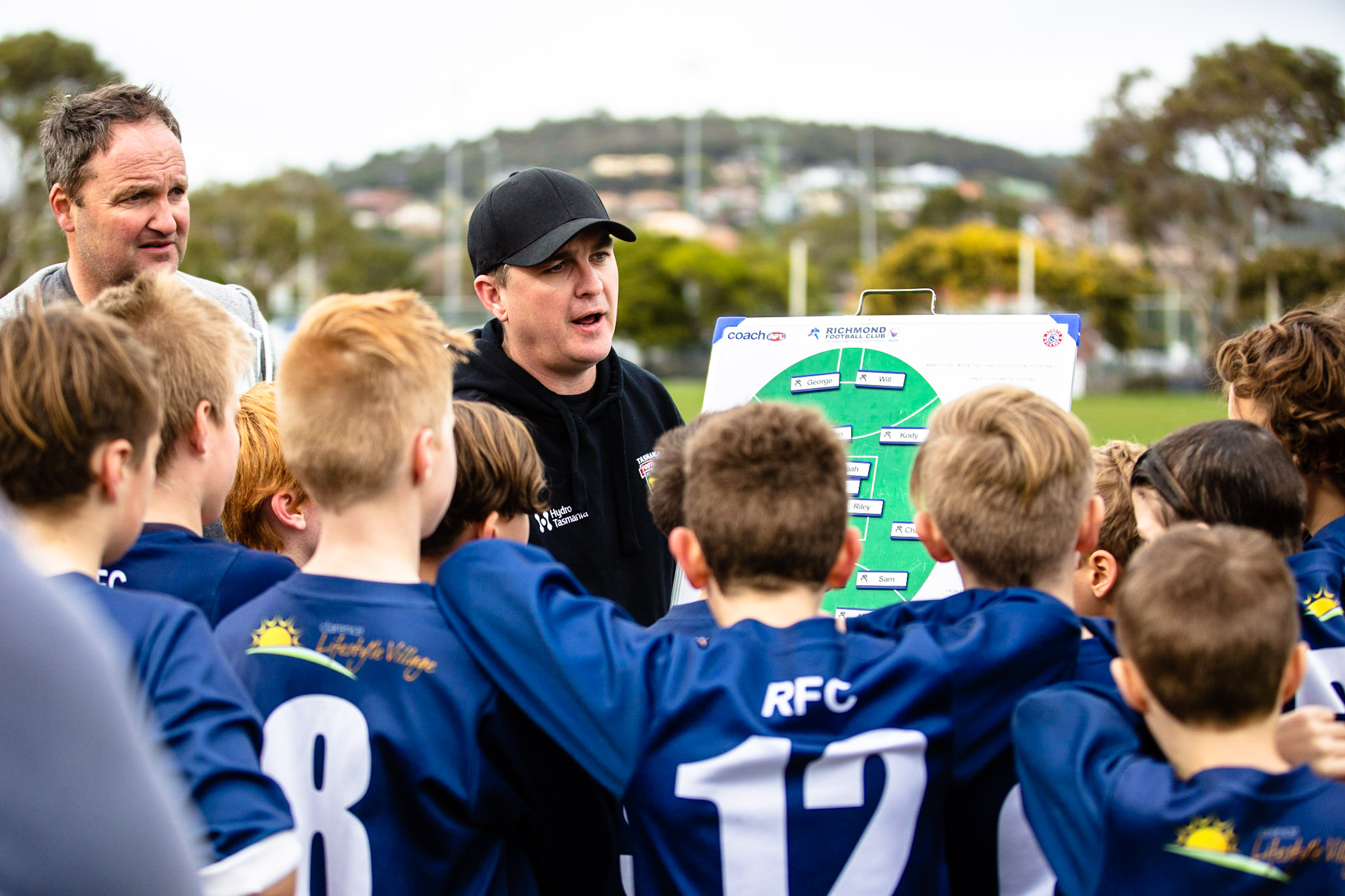 A coach talking to junior football players in a huddle