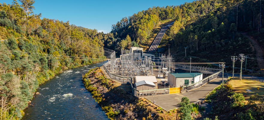 Aerial photo of Tarraleah Power Station, with the switchyard in front of the station and penstocks running down the hill. Next to the power station is the Nive River.