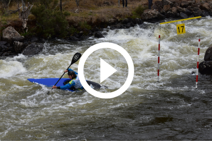 A National Canoe Slalom championships contestant, paddling down rapid waves in a blue canoe.