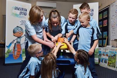A group of students standing around a model generator