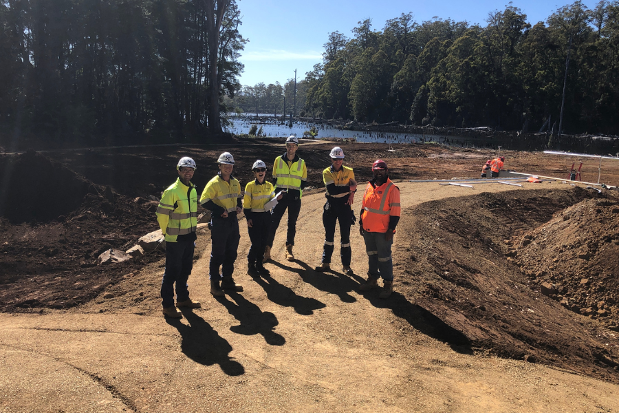 Oliver and his team standing posing for a photo. They are wearing high-vis and helmets. Blue sky and trees are behind them in the background.