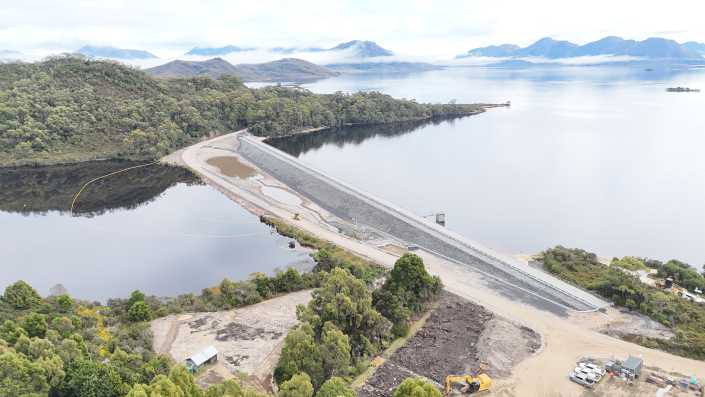 a landscape photo showing the upgraded edgar dam with lake pedder and nearby mountains in the background