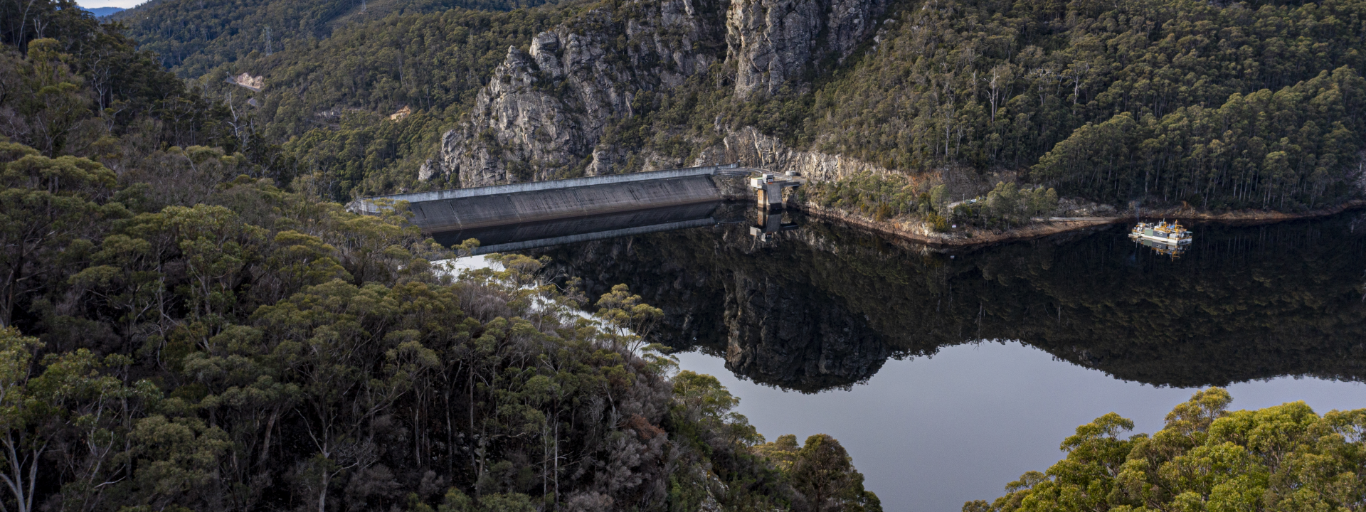 Dam surround by forest with cloudy skies