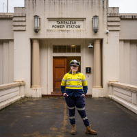 A woman in safety clothing standing outside a power station